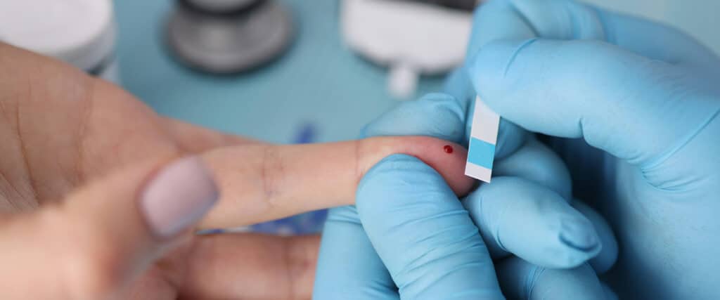 Bluttest an einem Finger mit Teststreifen