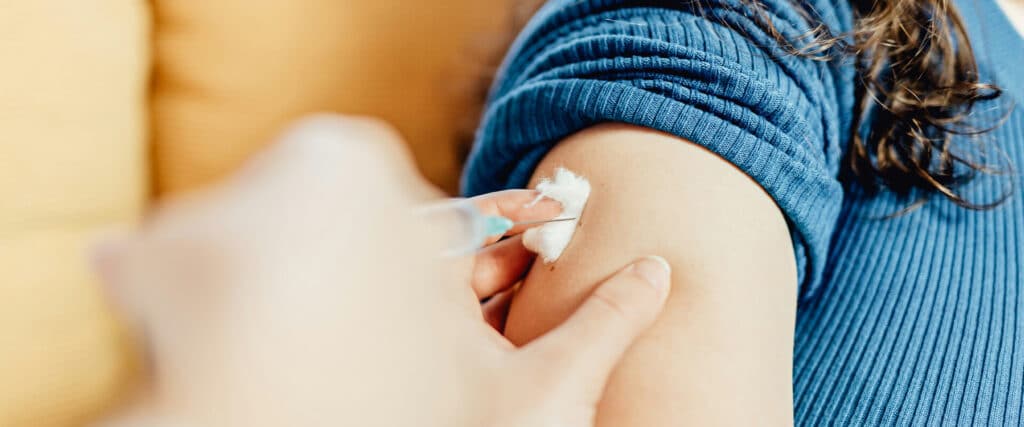 Impfung mit einer Spritze an dem Oberarm einer jungen Frau