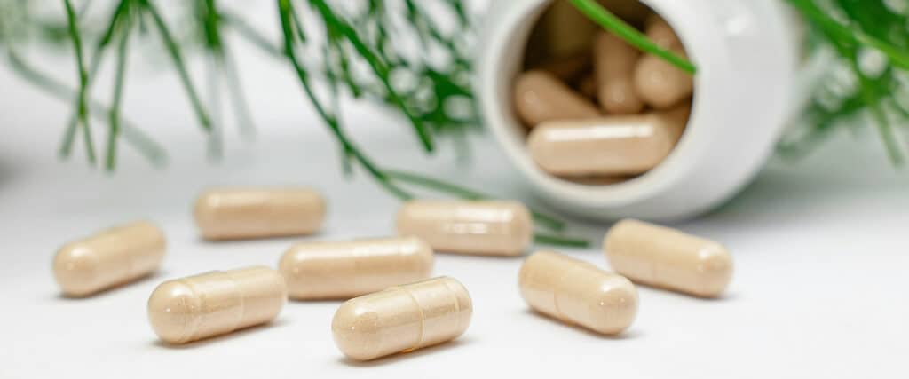 Nahrungsergänzungsmittel liegen in Kapselform verteilt auf einem weißen Tisch