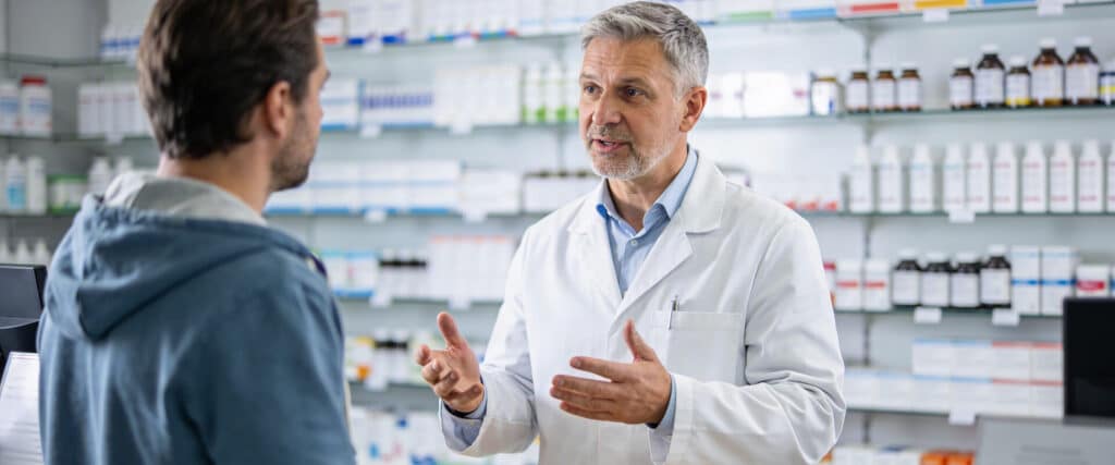 Apothekenreform 2026 Beitragsbild - Apotheker berät einen männlichen Kunden hinter den Tresen